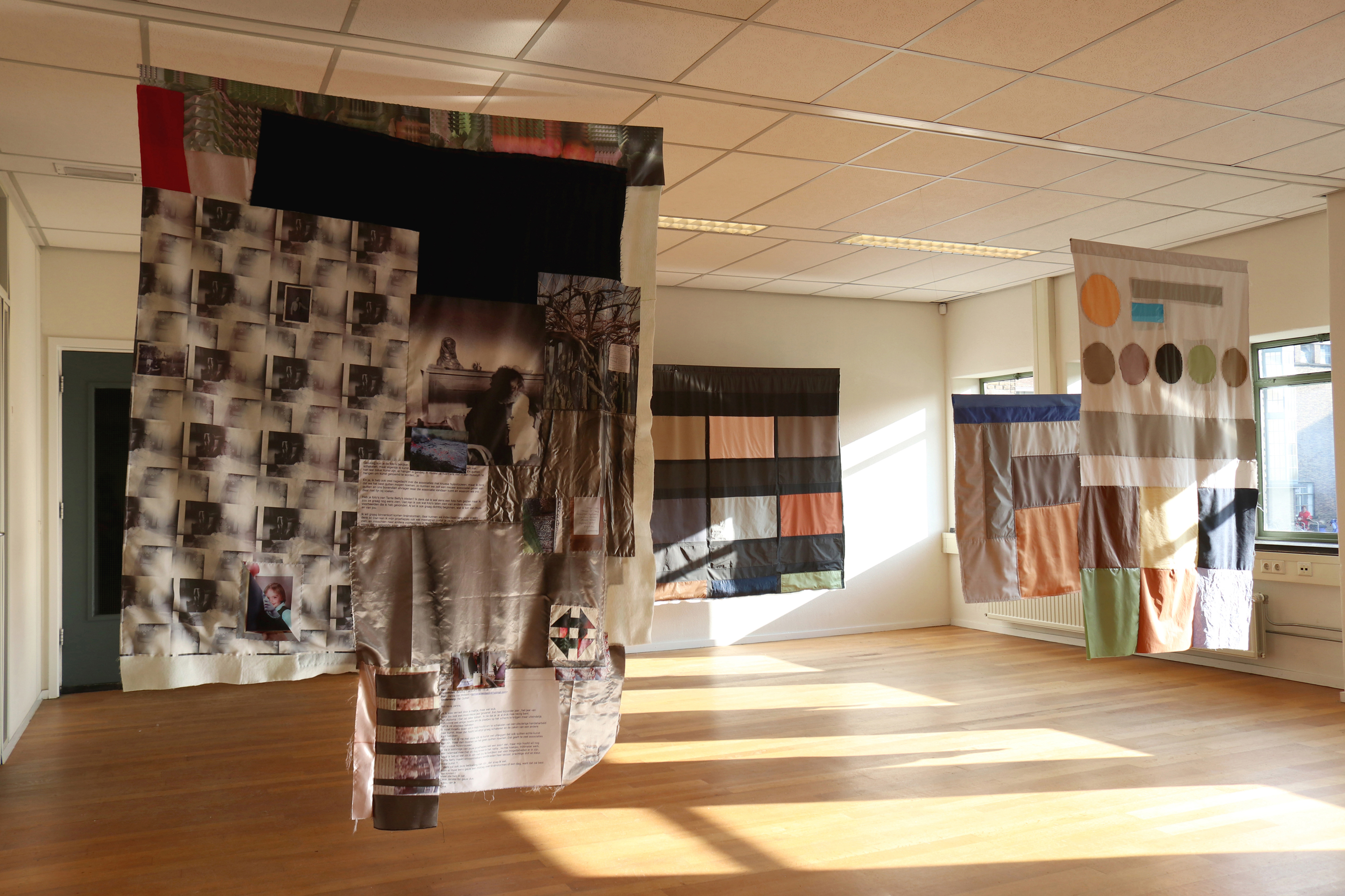 overview photo of the artist's graduation installation: 4 different quilts hung from the ceiling 